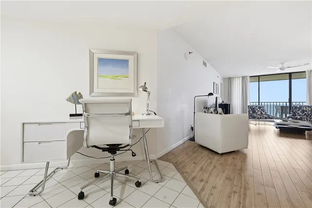 a living room with couches and kitchen view with wooden floor