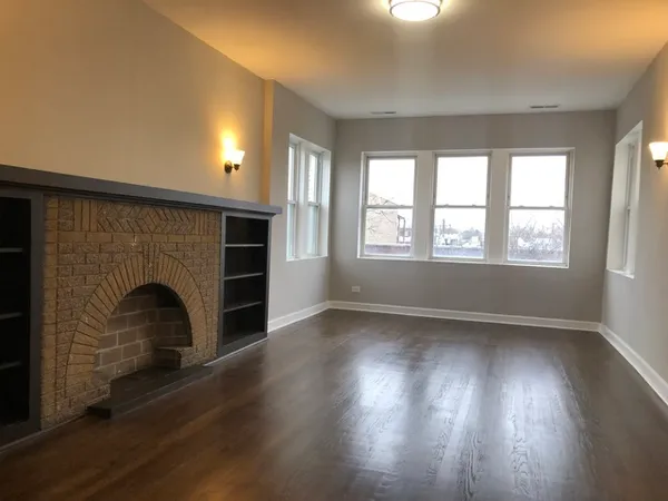 an empty room with windows and fireplace