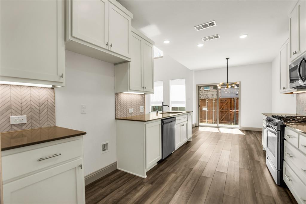 999 Emil Place Allen, TX 75013 - Photo 8 of 29 a kitchen with stainless steel appliances a stove a sink a refrigerator and white cabinets with wooden floor