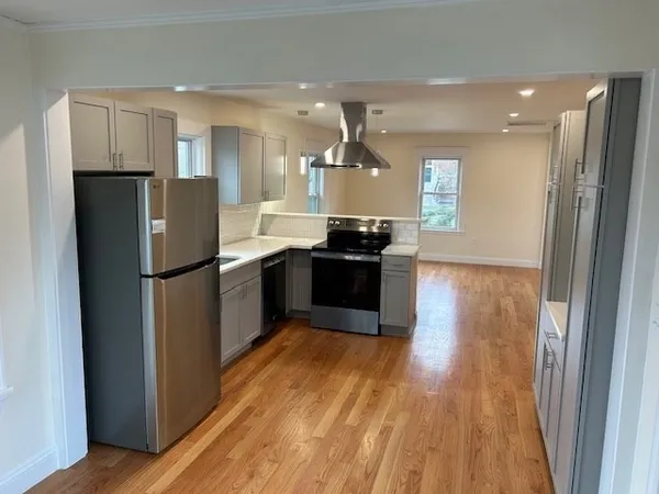 a kitchen with stainless steel appliances wooden floor and wooden cabinets