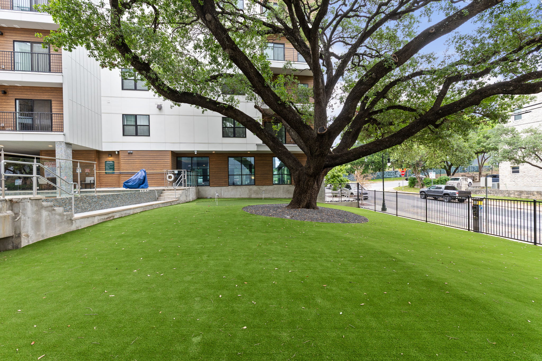2500 Longview Street, Unit 507 Austin, TX 78705 - Photo 37 of 37 Mature trees and lush artificial turf define this inviting outdoor space adjacent to a modern structure.