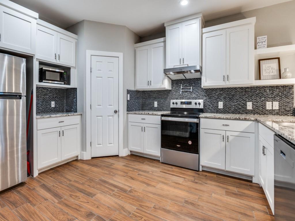 908 East Decatur Street Ennis, TX 75119 - Photo 11 of 22 a kitchen with stainless steel appliances granite countertop a stove and white cabinets