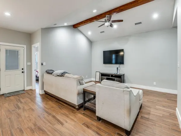 a living room with couches and kitchen view with wooden floor