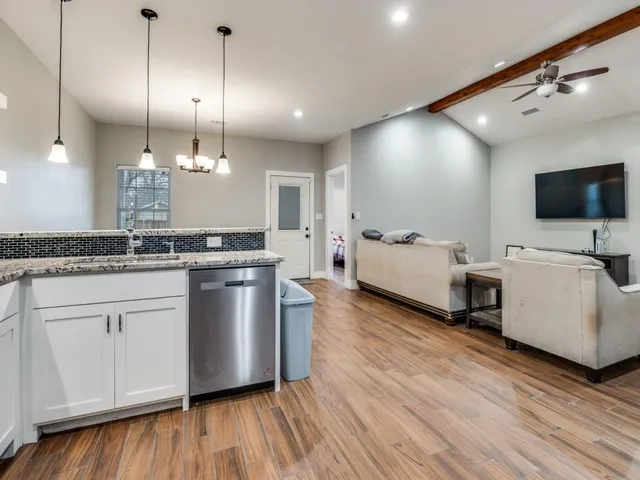 a kitchen with stainless steel appliances granite countertop wooden floor sink stove and white cabinets with wooden floor