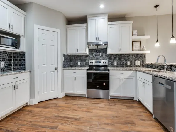 a kitchen with stainless steel appliances granite countertop a stove and white cabinets