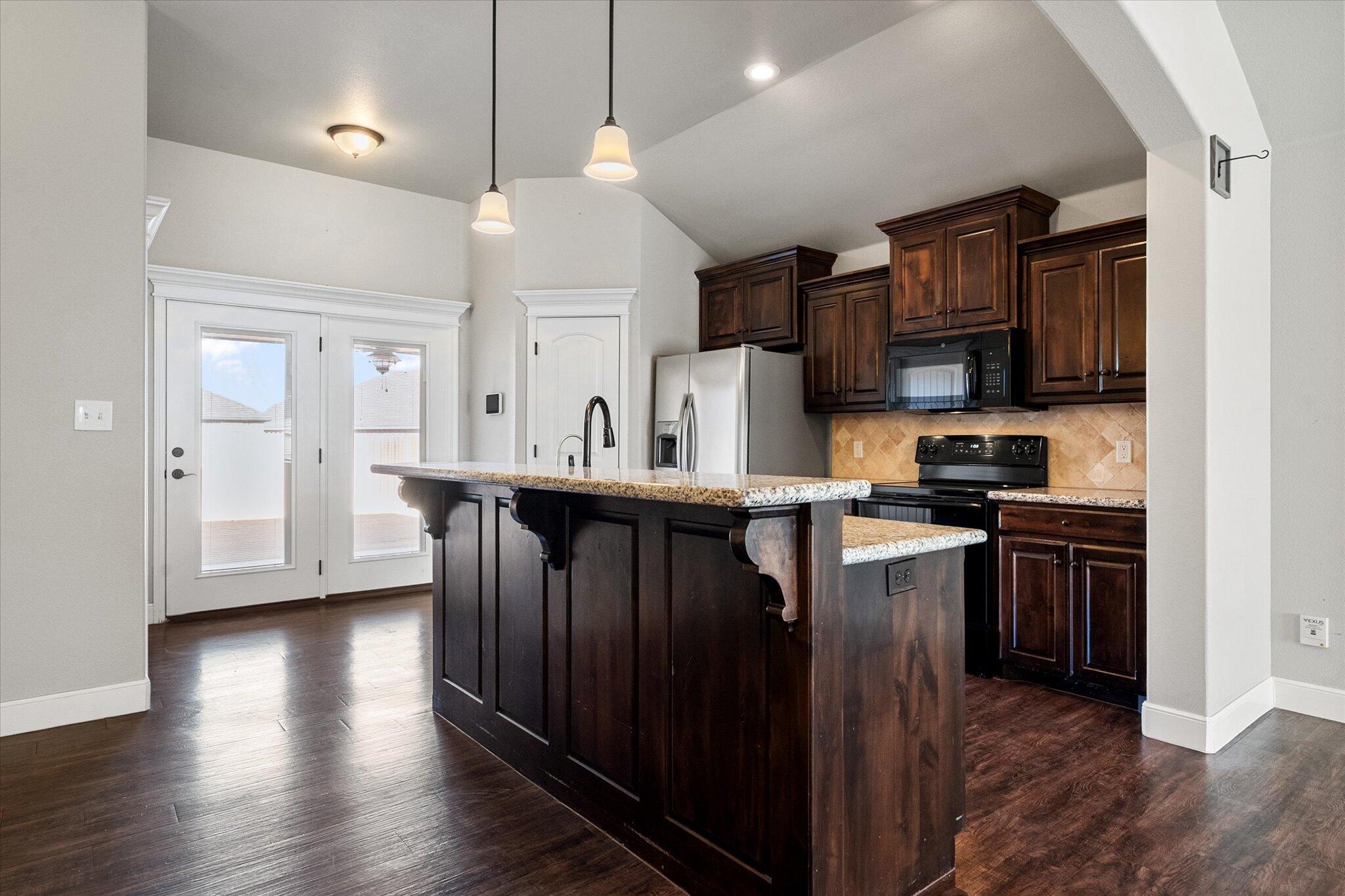 4916 Itasca Street Lubbock, TX 79416 - Photo 12 of 27 a kitchen with stainless steel appliances granite countertop a refrigerator a sink dishwasher a stove and white cabinets with wooden floor
