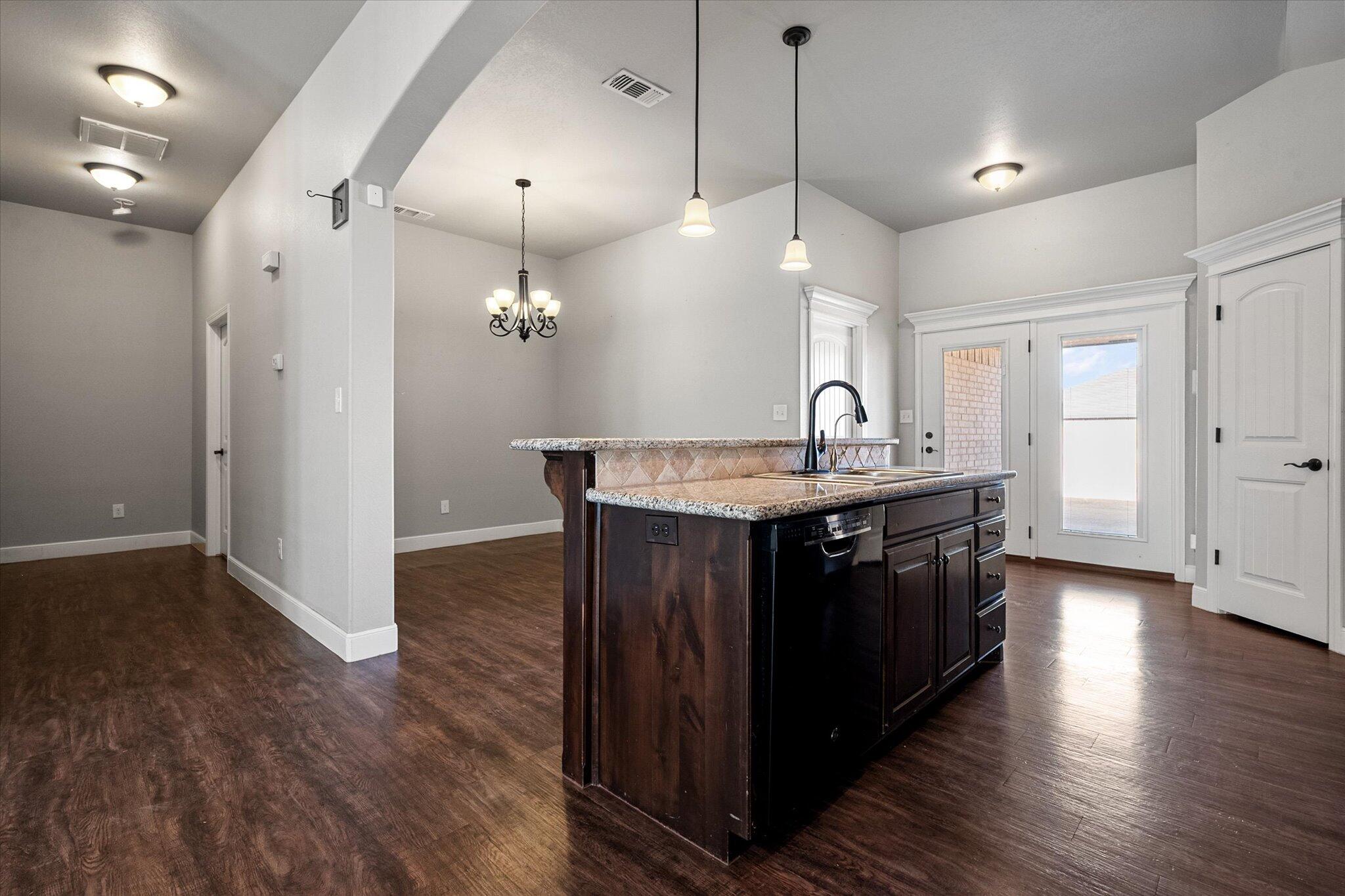 4916 Itasca Street Lubbock, TX 79416 - Photo 13 of 27 a kitchen with kitchen island granite countertop a sink cabinets and wooden floor