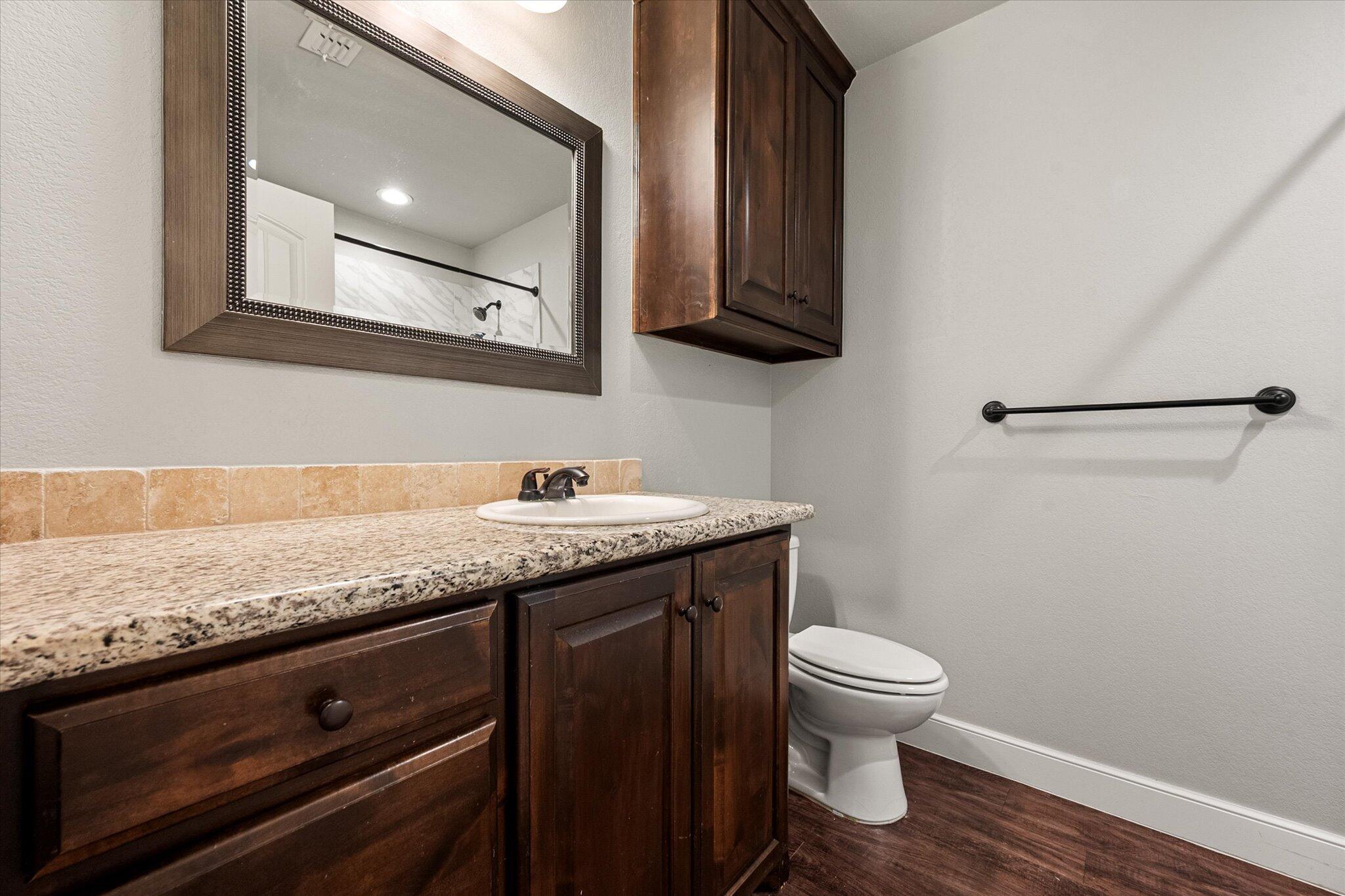 4916 Itasca Street Lubbock, TX 79416 - Photo 20 of 27 a bathroom with a granite countertop toilet sink and mirror