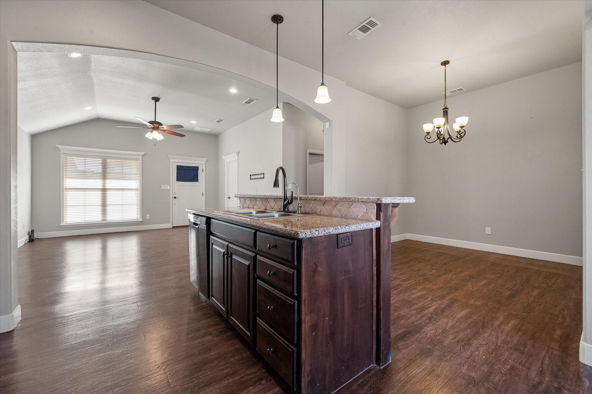 4916 Itasca Street Lubbock, TX 79416 - Photo 9 of 27 a kitchen with granite countertop a stove a sink a center island and a wooden floor