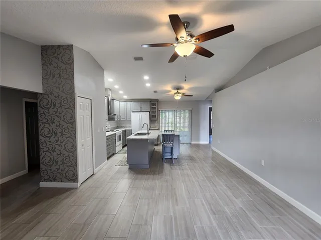 a living room with couches and kitchen view with wooden floor