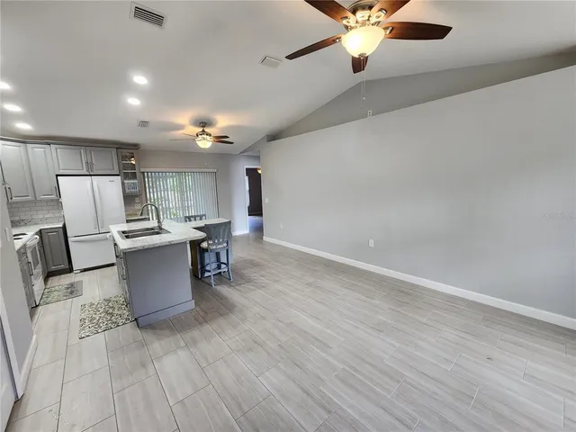 a large kitchen with a stove a sink dishwasher a kitchen island with wooden cabinets and floor