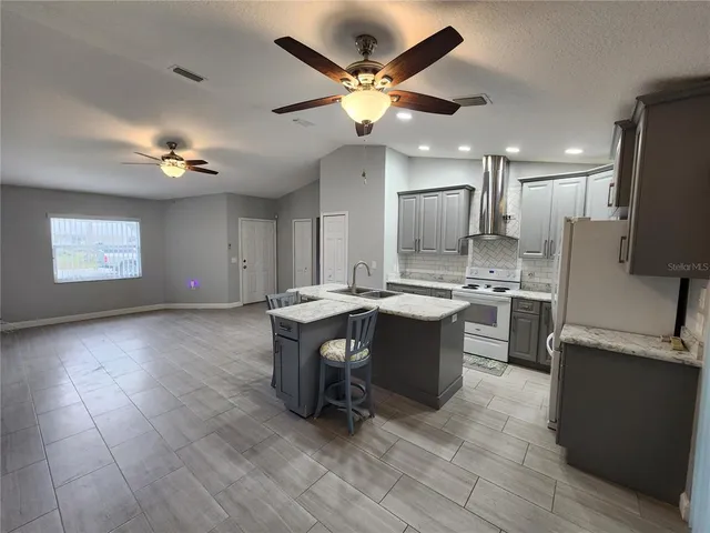 a kitchen with stainless steel appliances granite countertop a table chairs sink and refrigerator