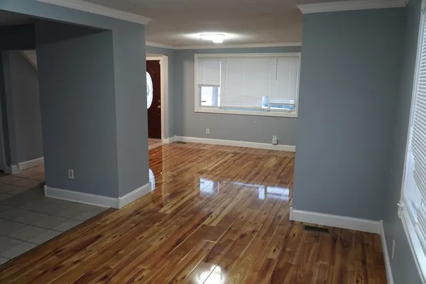 an empty room with wooden floor and windows