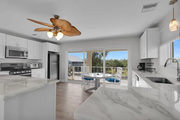 a kitchen with stainless steel appliances granite countertop a stove a refrigerator a sink a stove and white cabinets with wooden floor