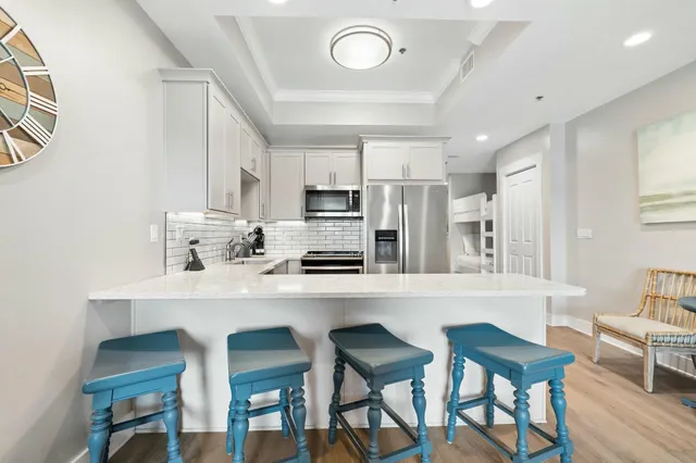 a kitchen with stainless steel appliances a dining table chairs refrigerator and sink