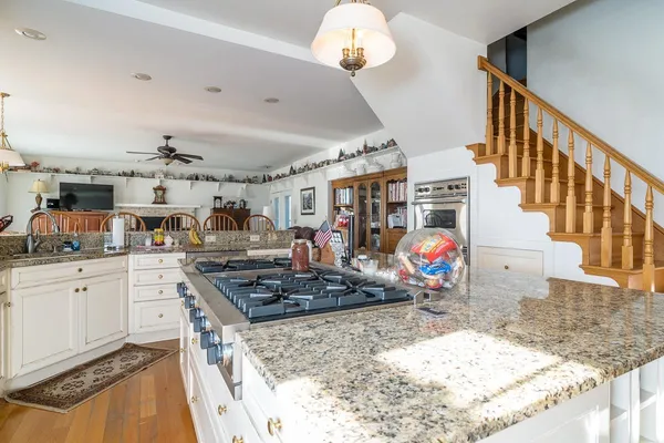 a kitchen with stainless steel appliances granite countertop a sink dishwasher and white cabinets with wooden floor