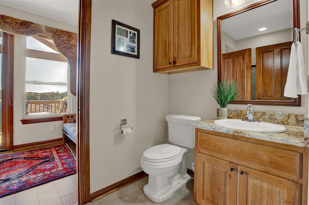 5300 Lookout Ridge Drive Marble Falls, TX 78654 - Photo 19 of 40 a bathroom with a granite countertop sink mirror vanity and toilet