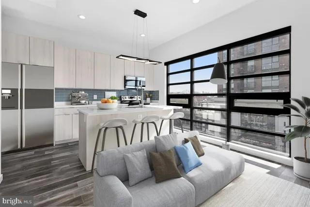 a living room with furniture a rug and white kitchen view