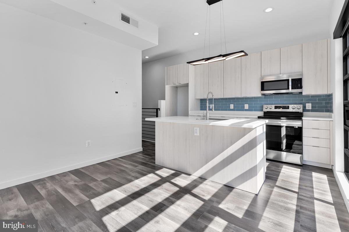 506 H Street Northeast, Unit 401 Washington, DC 20002 - Photo 7 of 19 a large white kitchen with stainless steel appliances granite countertop a sink and cabinets