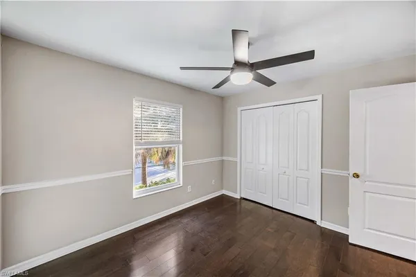 an empty room with wooden floor ceiling fan and windows