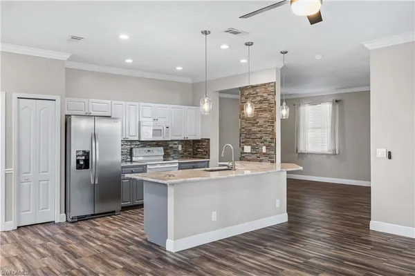 a kitchen with stainless steel appliances granite countertop a refrigerator a sink dishwasher a stove and white countertops with wooden floor