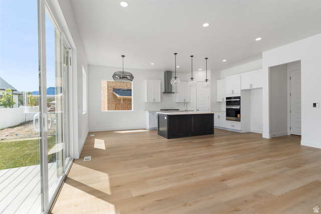 43 South Crimson Way, Unit 311 Mapleton, UT 84664 - Photo 6 of 28 Open-concept kitchen and living area featuring wood-finish flooring, a two-tone kitchen island with pendant lighting, white cabinetry, and stainless steel appliances