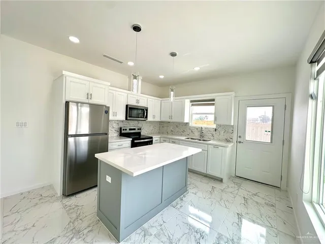 a kitchen with a sink a counter top space stainless steel appliances cabinets and a window