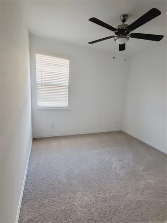 an empty room with a window and a fan