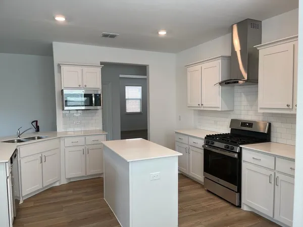 a kitchen with white cabinets and appliances