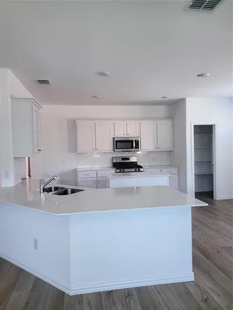 a kitchen with kitchen island a sink a stove and cabinets