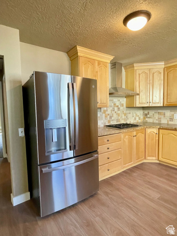 255 West Main Street Mount Pleasant, UT 84647 - Photo 6 of 35 Stainless steel French door refrigerator, wood-finish flooring, light wood cabinetry, stone-look countertops, and a tiled backsplash