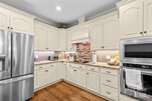 a kitchen with granite countertop a refrigerator stove and white cabinets