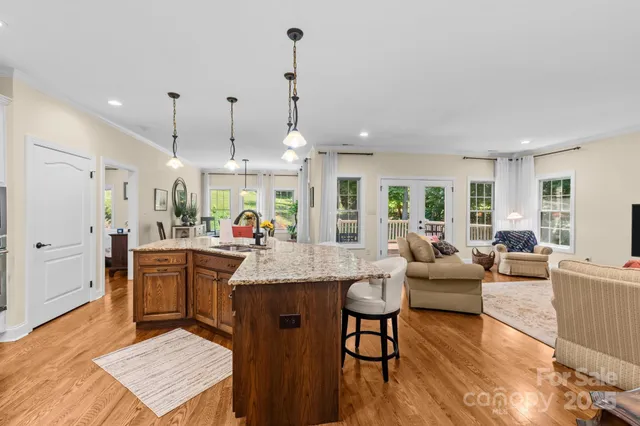 a living room with furniture kitchen view and a wooden floor