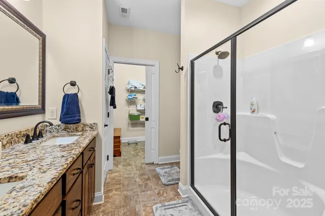 a bathroom with a granite countertop sink a mirror and shower
