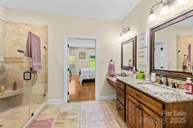 a bathroom with a granite countertop sink a mirror and a shower