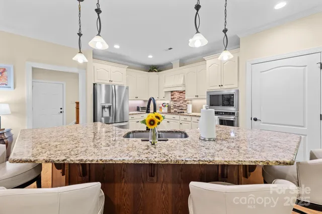 a kitchen with stainless steel appliances kitchen island granite countertop a table and chairs in it