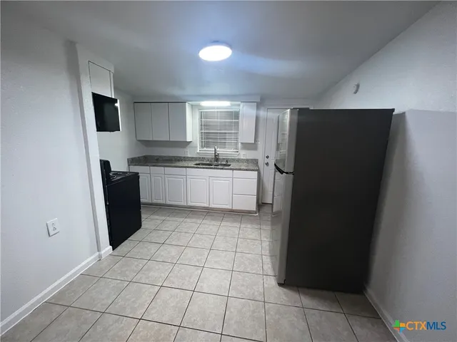a kitchen with a refrigerator a stove top oven and a sink