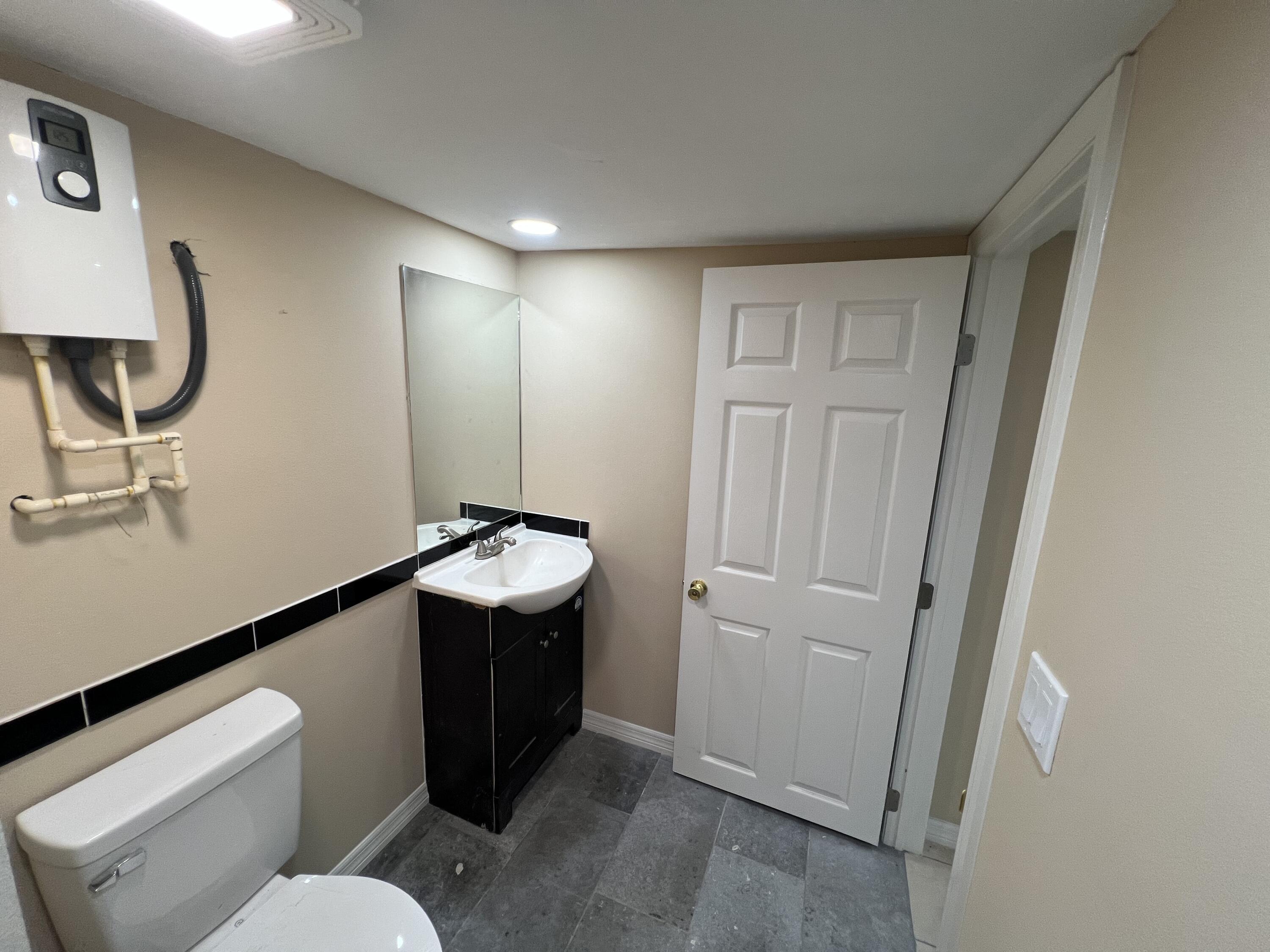 5728 St Lucie Boulevard, Unit REAR HOUSE Fort Pierce, FL 34946 - Photo 18 of 22 a bathroom with a sink vanity mirror and toilet