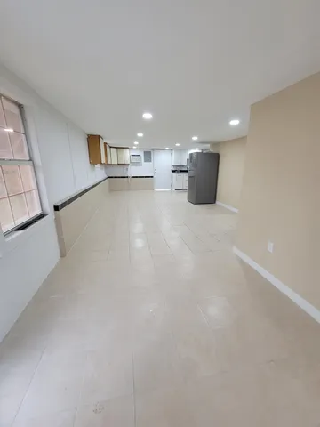 a view of empty room with kitchen and window