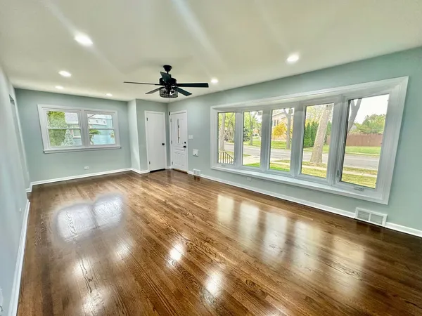 a view of an empty room with a window and wooden floor