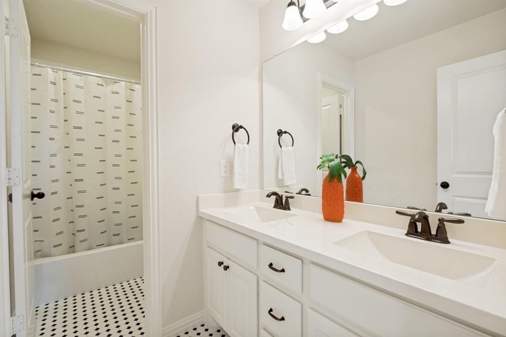 14215 Raspberry Lane Frisco, TX 75035 - Photo 15 of 30 Double vanity with integrated sinks, white cabinetry, dark bronze hardware, and a framed mirror