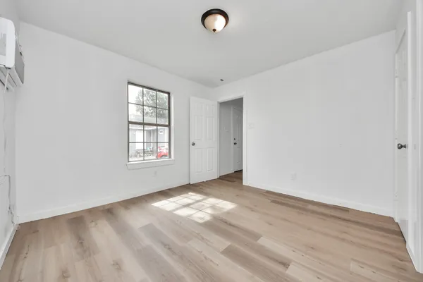 an empty room with wooden floor and windows