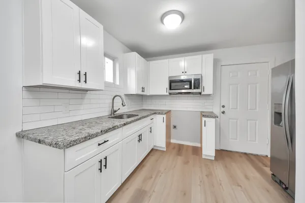 a kitchen with granite countertop a sink stove and refrigerator