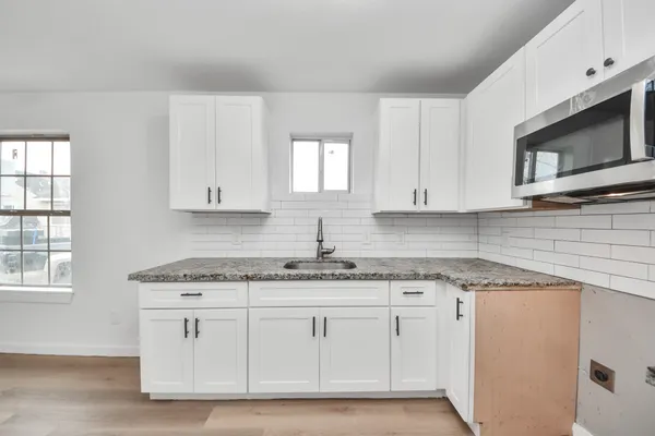 a kitchen with granite countertop white cabinets white appliances and a sink