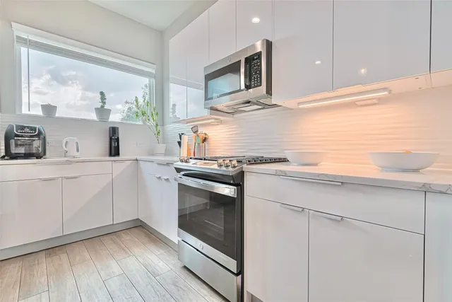 a kitchen with stainless steel appliances white cabinets and a stove top oven