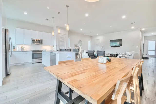 a large kitchen with kitchen island a stove a sink a refrigerator and a dining table