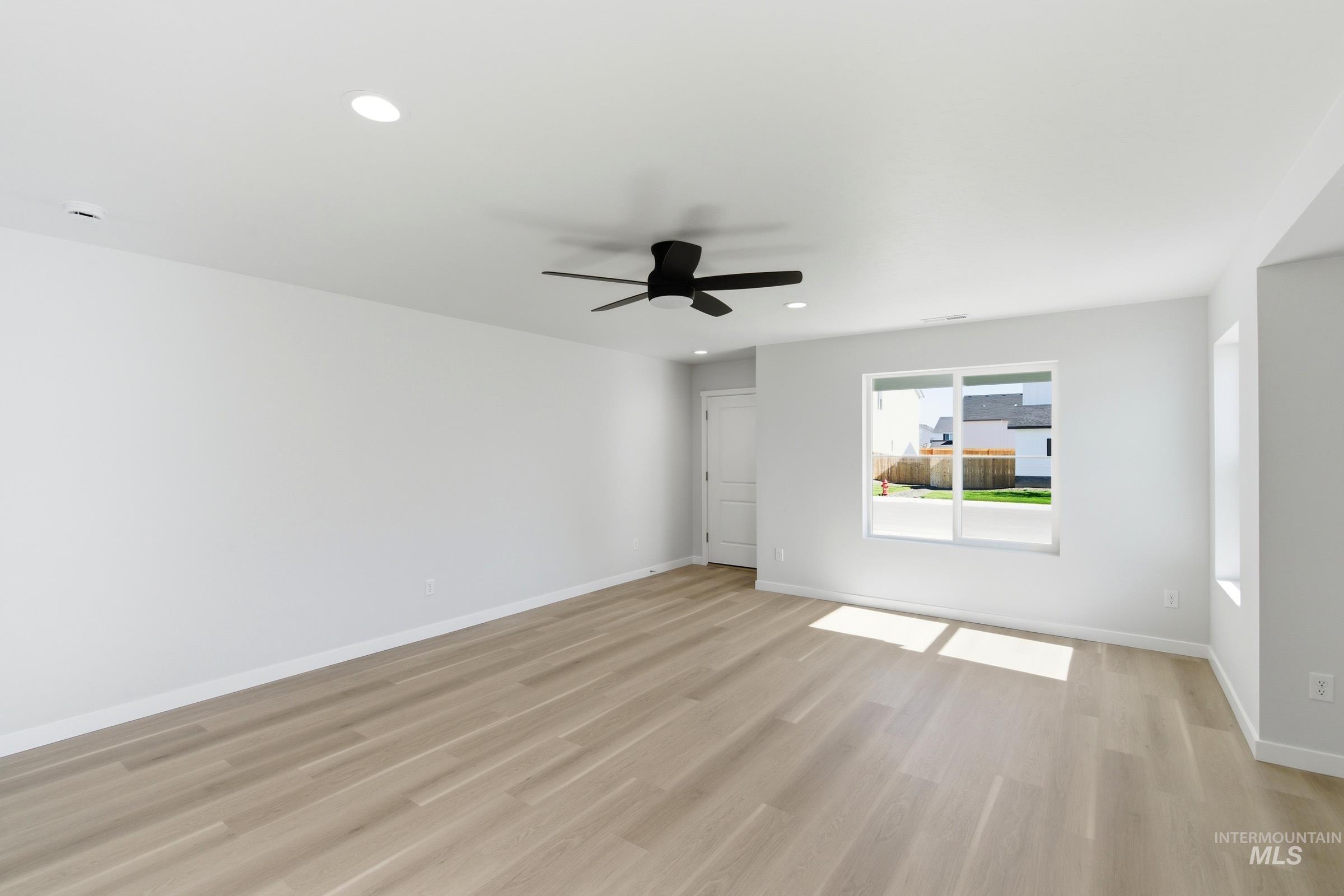 13677 Redway Court Caldwell, ID 83607 - Photo 16 of 35 Spacious room featuring light wood-finish flooring, recessed ceiling lighting, a contemporary black ceiling fan, and large windows providing natural illumination