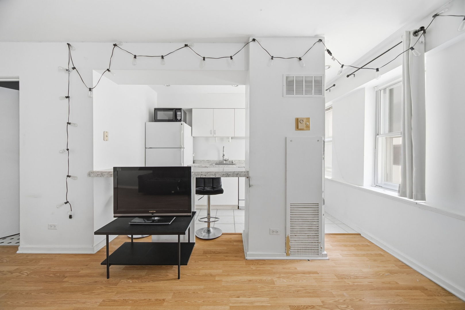 40 East 9th Street, Unit 712 Chicago, IL 60605 - Photo 5 of 26 a living room with furniture a flat screen tv and a refrigerator