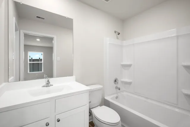 a bathroom with a bathtub shower sink vanity mirror and toilet