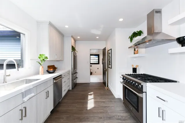 a kitchen with stainless steel appliances a sink dishwasher stove refrigerator and wooden floor